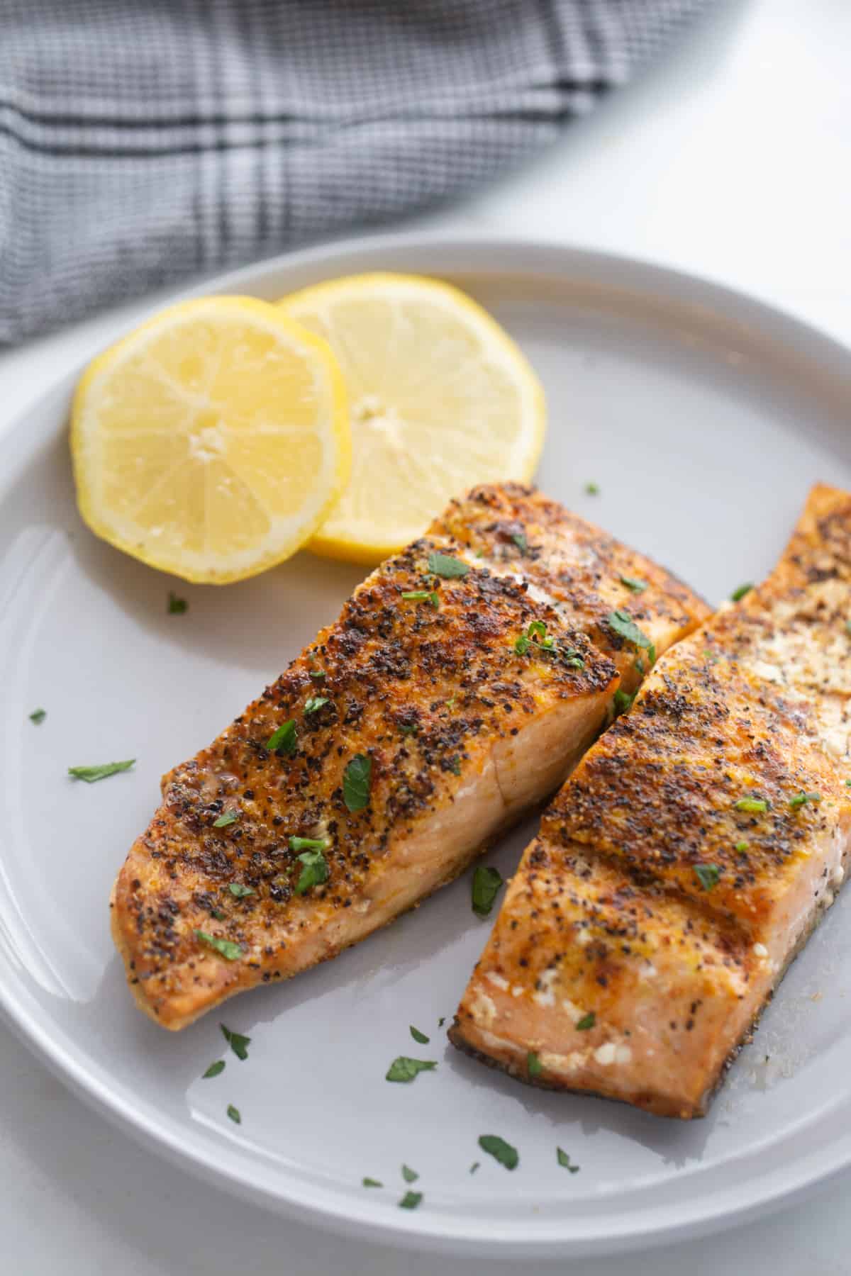 Perfectly cooked salmon fillets made in the air fryer garnished with fresh herbs. 