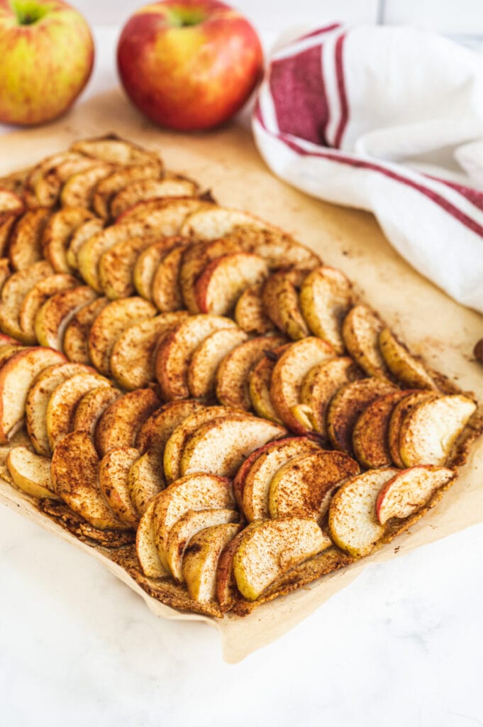 Baking sheet with sliced apples topped with cinnamon on a Gluten Free crust