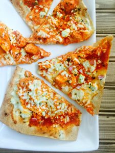 Flatbread pizza cut into triangles topped with buffalo chicken, ricotta, blue cheese, and mozzarella cheese from the blog, Confessions of a Fit Foodie.