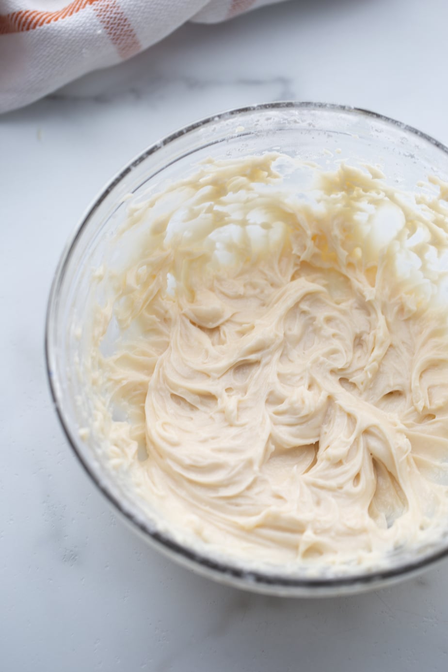 Lightened up cream cheese frosting whipped in a glass bowl