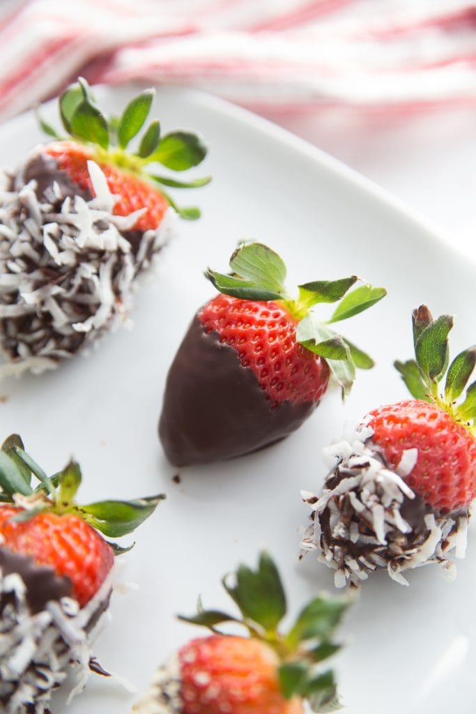 A plate of chocolate covered strawberries with various toppings