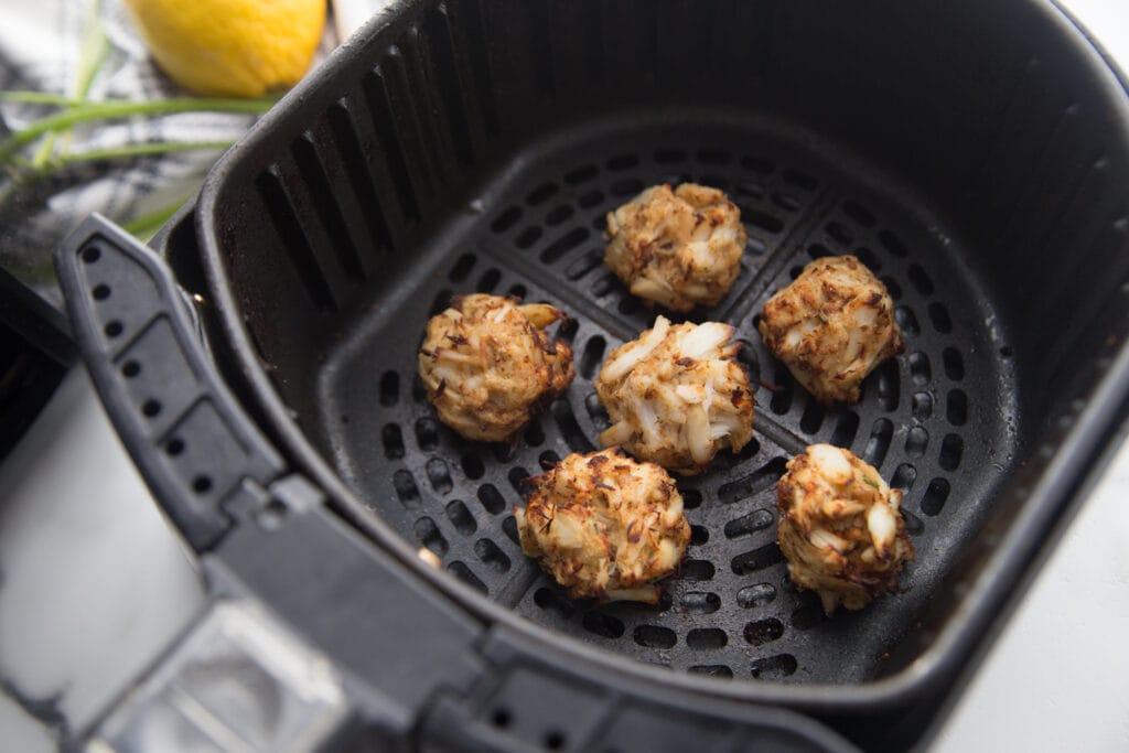 Air fryer basket with mini crab cakes that are gluten free