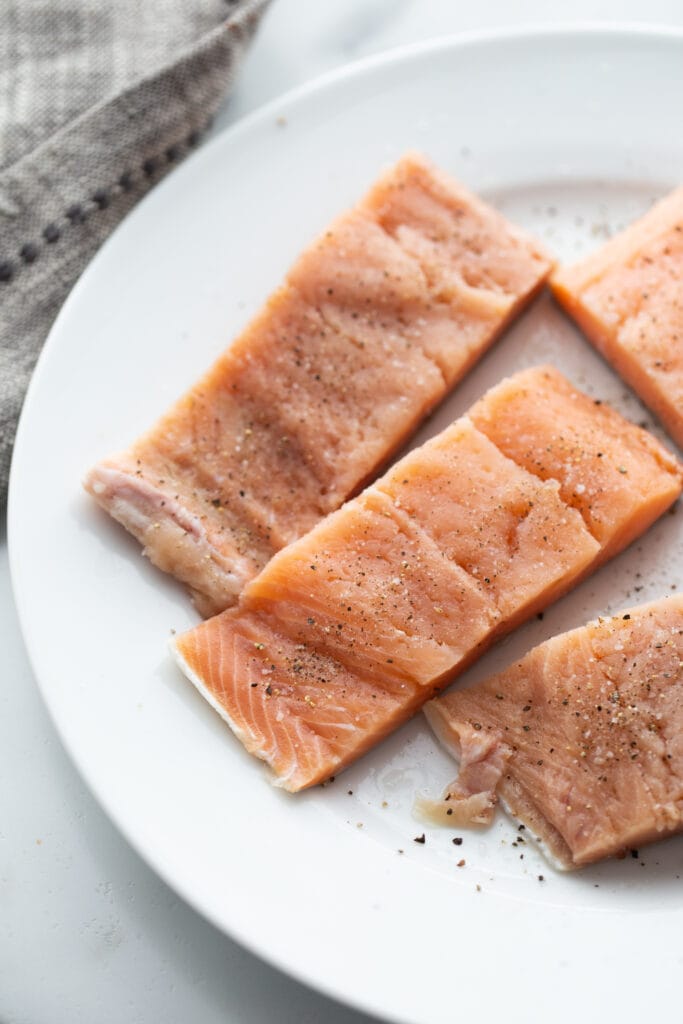 Raw salmon fillets seasoned with salt and pepper.