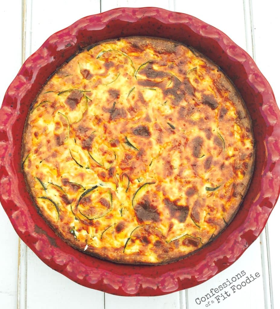 Overhead view of crustless zucchini quiche, a recipe from the blog Confessions of a Fit Foodie, served in a red round pie plate 