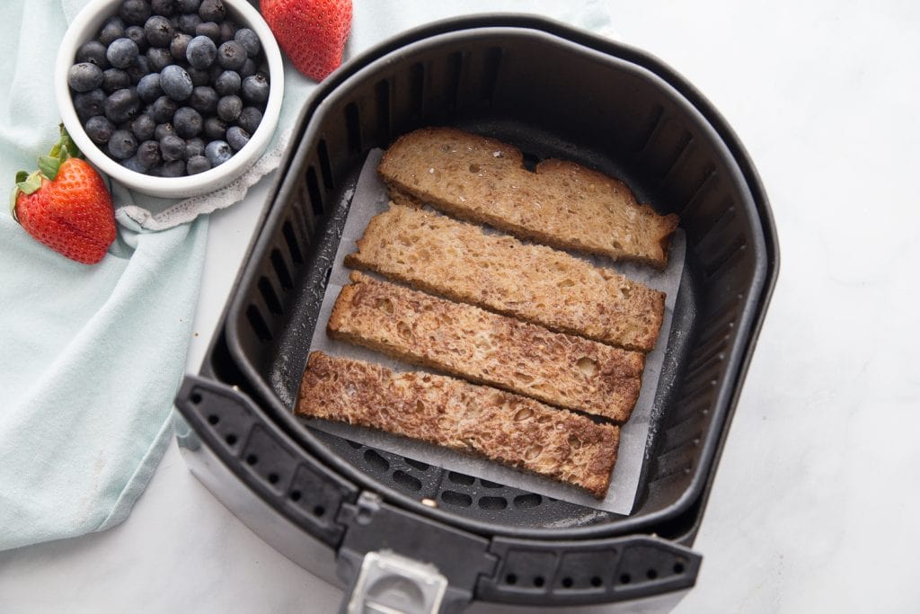 An airfryer basket lined with french toast sticks 