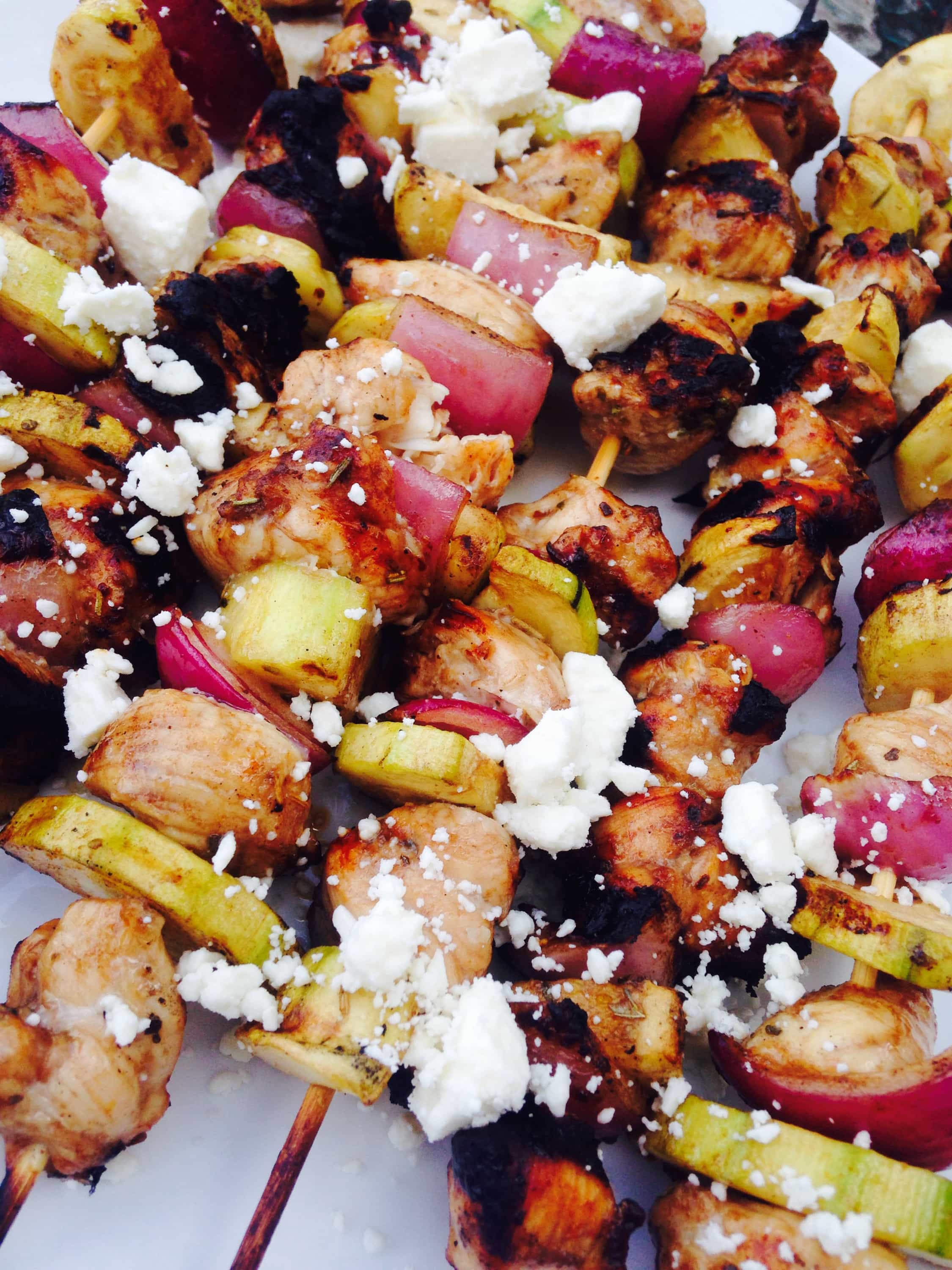 Balsamic marinated chicken, zucchini, and red onion are alternated on skewers and grilled, then topped with feta.