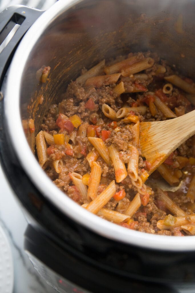 A wooden spoon mixing Instant Pot Enchilada Pasta for the 21 Day Fix 