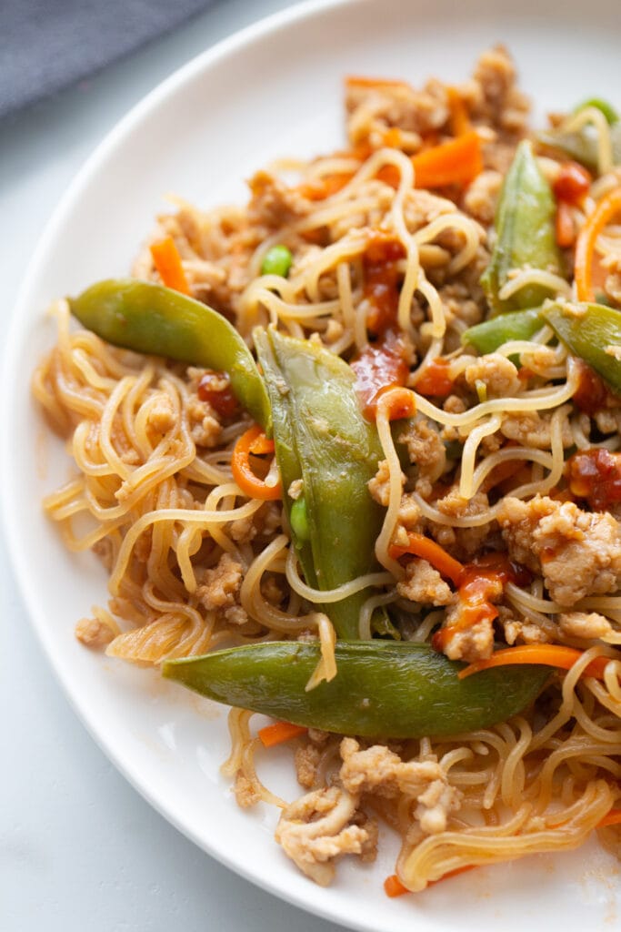 Overhead image: Ramen noodles with stir fried vegetables and ground chicken on a white plate