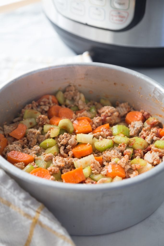 Instant Pot next to an aluminum insert with ground turkey, carrots, and celery 