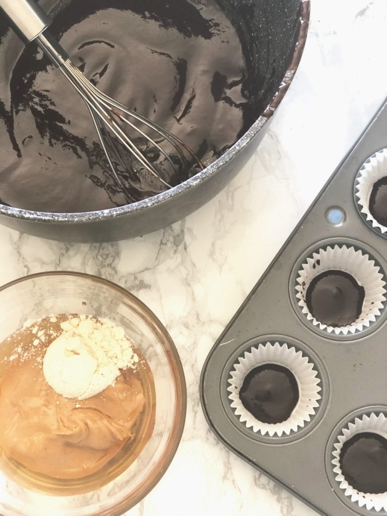A cupcake tin, peanut butter, and a saucepan of homemade chocolate ready to make peanut butter cups 