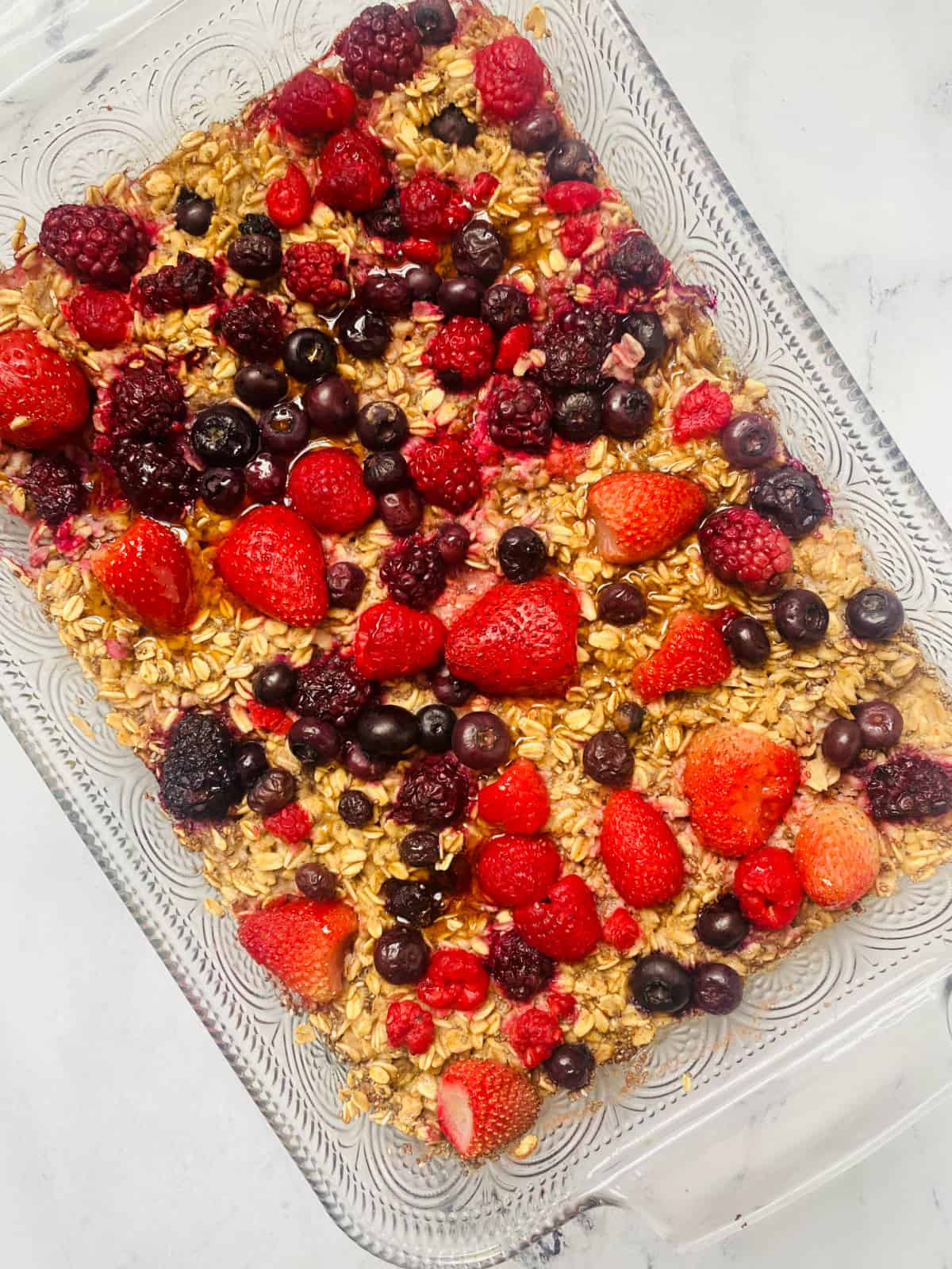 A baking dish of baked oats topped with frozen berries just pulled out of the oven. 