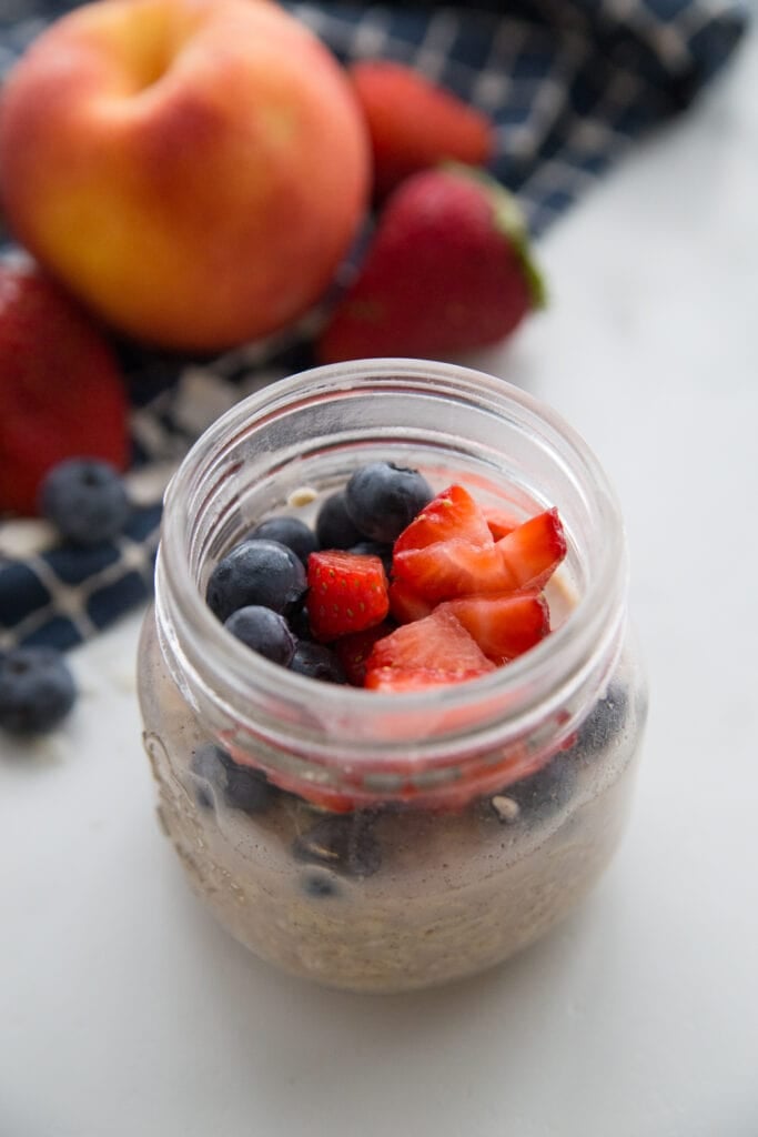 A jar of very berry overnight oats topped with blueberries and strawberries 