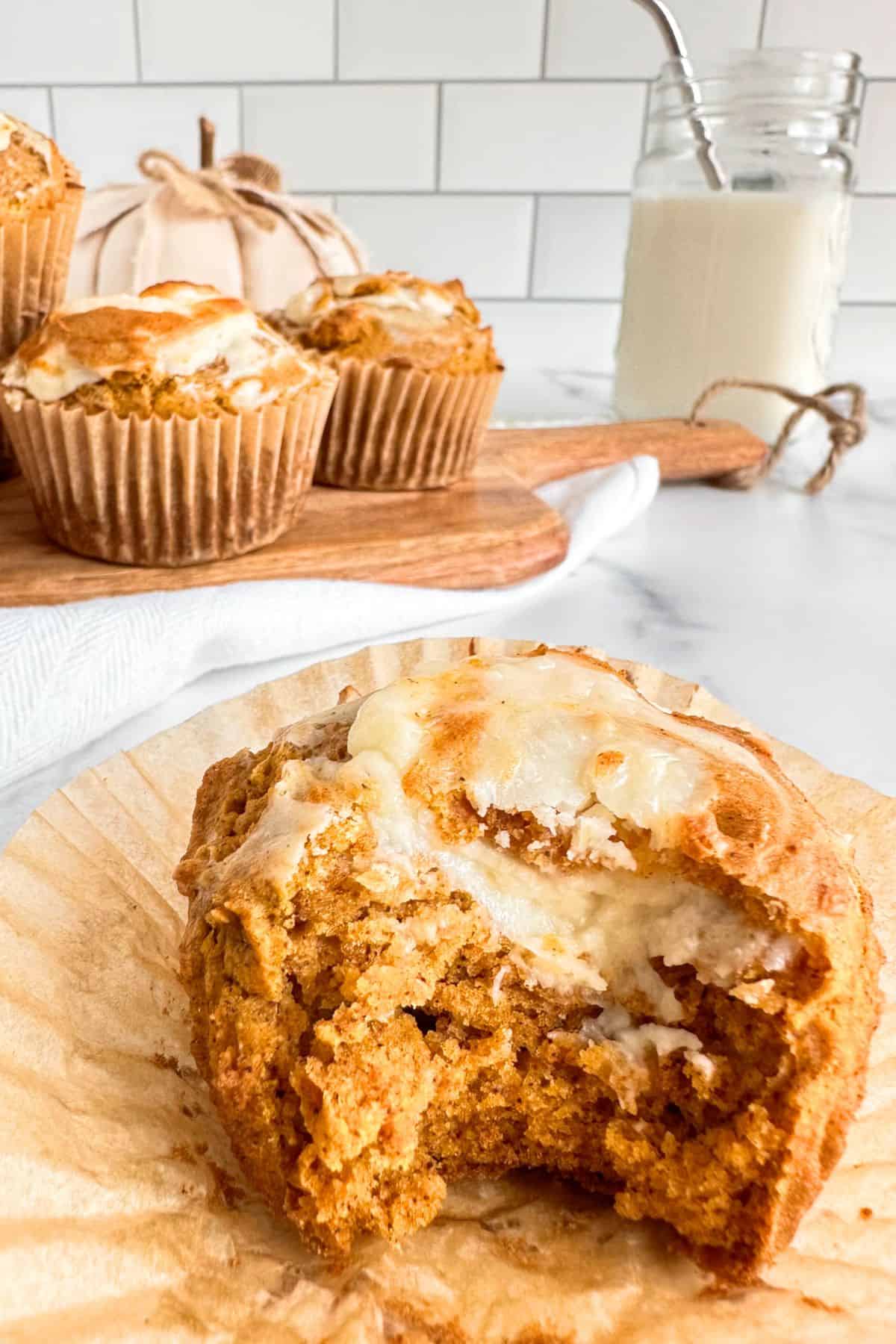 Healthy pumpkin cheesecake muffin with a bit taken out of it to show the cream cheese filling.