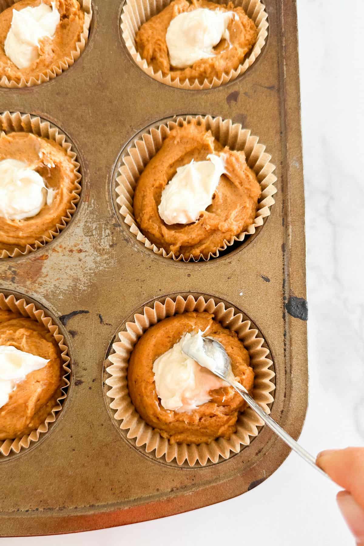 Filling pumpkin muffins with cream cheese.