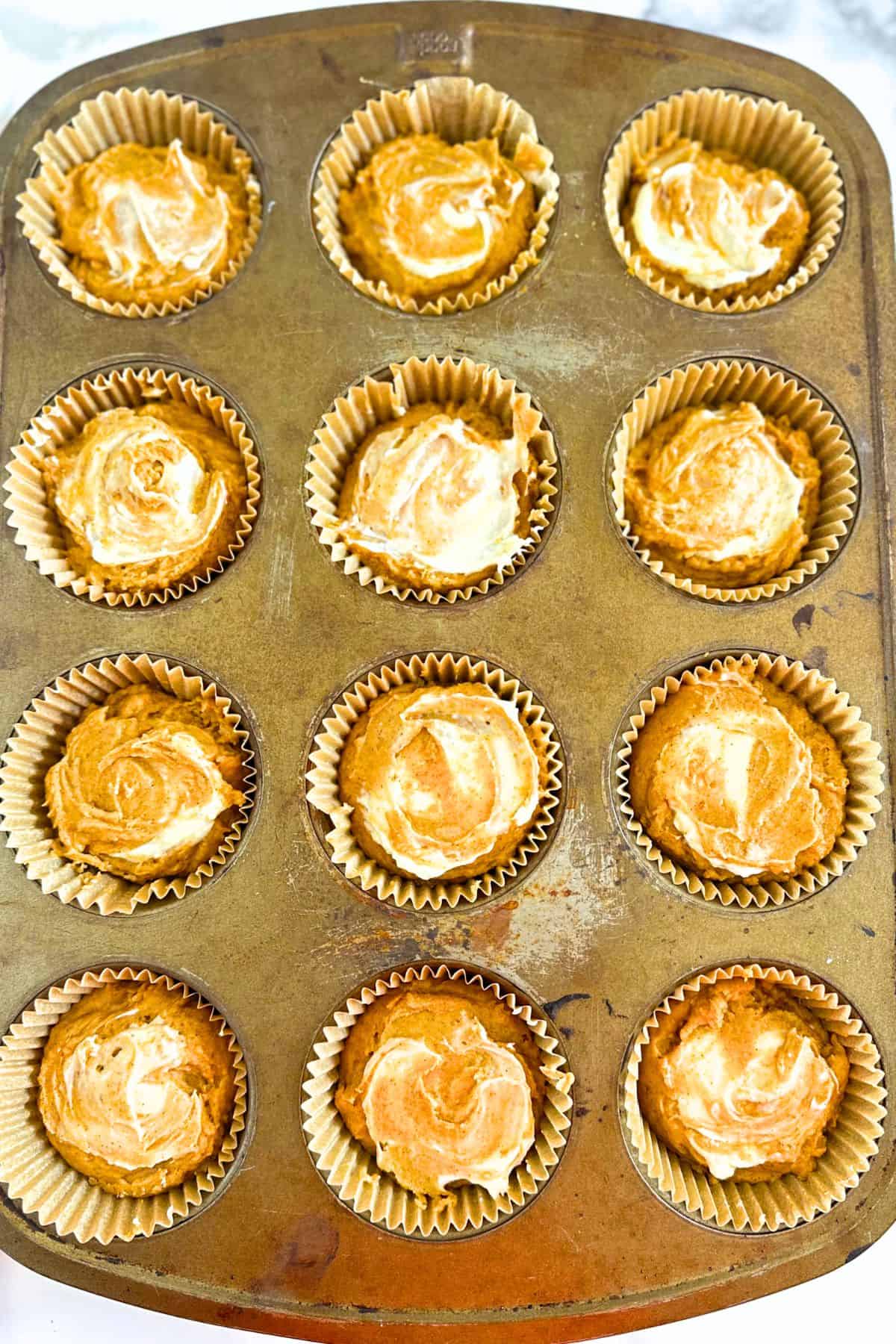 Cream cheese swirled on top of healthy pumpkin muffins.