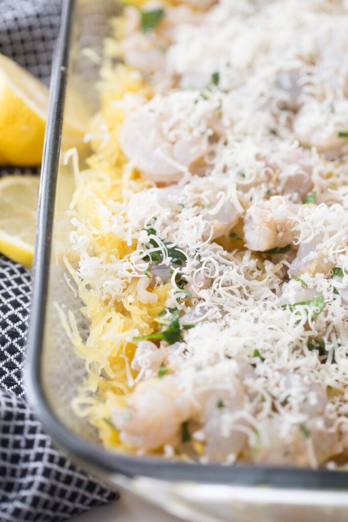 freshly grated parmesan cheese on top of a spaghetti squash casserole, ready for baking