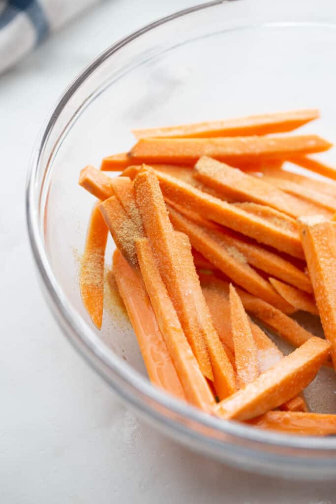 A bowl of sweet potato fries tossed with egg whites and seasonings.