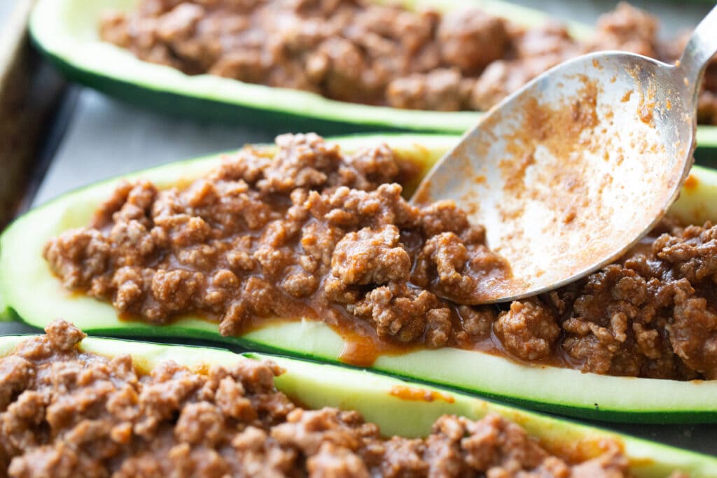 Close up photo of a spoon stuffing Zucchini boats ground beef mixture