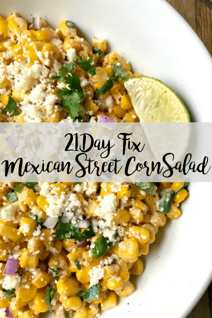 A white bowl filled with Mexican street corn salad topped with cotija cheese and cilantro with a lime wedge on the side- with the text overlay 21 Day Fix mexican street corn salad